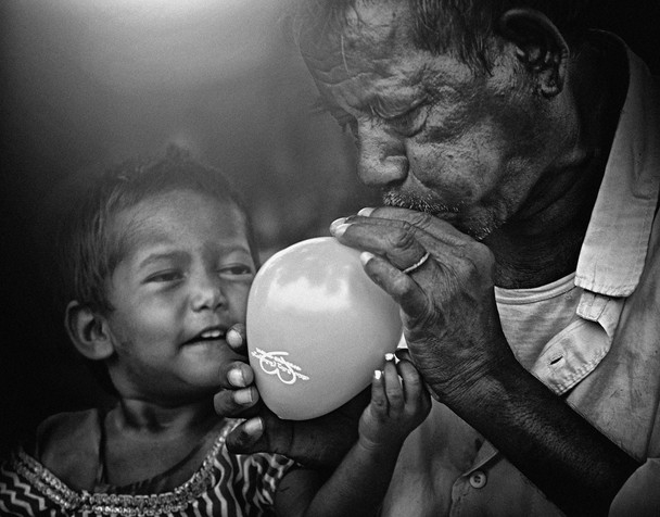 India: Grandfather giving a balloon to his grandson.